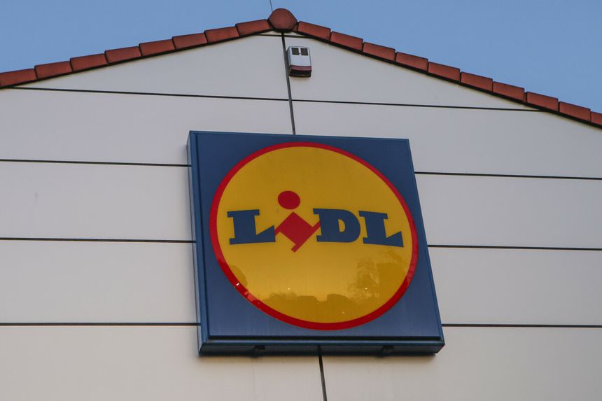 Logo sieci sklepów Lidl na ścianie budynku, w tle błękitne niebo.