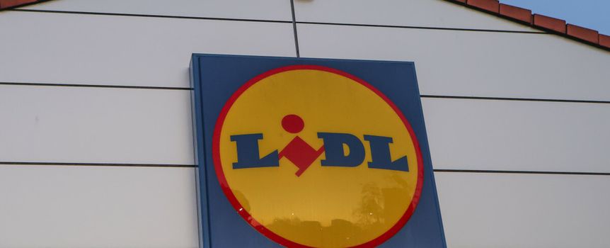 Logo sieci sklepów Lidl na ścianie budynku, w tle błękitne niebo.