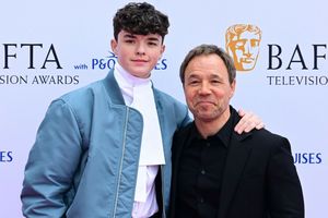 Na zdjęciu dwóch mężczyzn uśmiecha się na tle banera BAFTA. Mężczyźni ubrani elegancko.