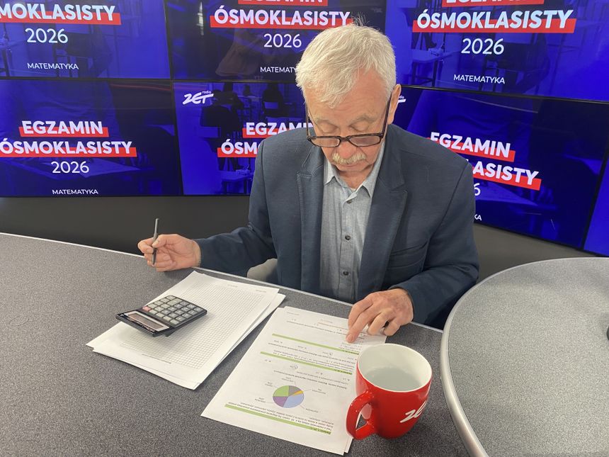 Mężczyzna w okularach przegląda dokumenty i kalkulator w studio radiowym. W tle hasła o egzaminie.
