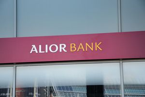 Witryna banku z napisem „ALIOR BANK” na czerwonym tle. Brak rozpoznawalnych postaci.