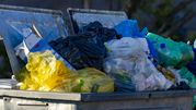 Złomowana śmietnik z różnokolorowymi workami na śmieci, pełen odpadków i zużytych opakowań.