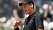 Jannik Sinner w czarnej koszulce, z zaciętą miną, triumfuje po udanym zagraniu.