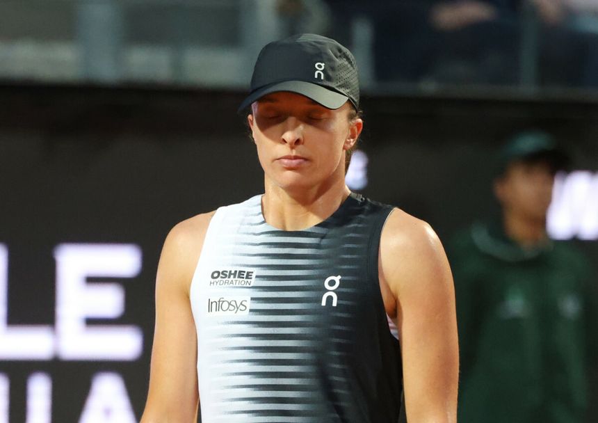 Na zdjęciu Iga Świątek stoi z zamkniętymi oczami, ubrana w sportowy strój i czapkę.