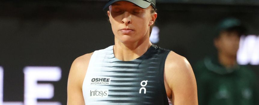 Na zdjęciu Iga Świątek stoi z zamkniętymi oczami, ubrana w sportowy strój i czapkę.