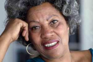 Na zdjęciu widoczna uśmiechnięta Toni Morrison z kręconymi włosami, podpierająca głowę ręką.