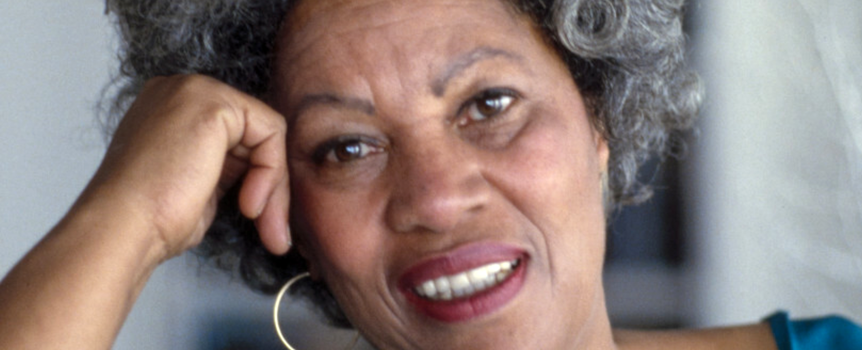 Na zdjęciu widoczna uśmiechnięta Toni Morrison z kręconymi włosami, podpierająca głowę ręką.