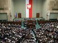 Zgromadzenie w Sejmie, z flagą Polski i orłem na ścianie, wielu przedstawicieli w sali.
