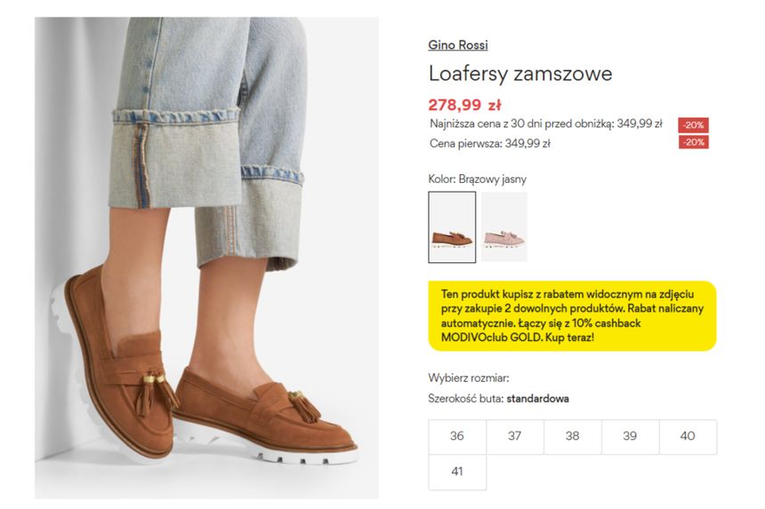 Brązowe loafersy zamczowe na białej podeszwie, widok z boku, na stopie modelki w dżinsach.
