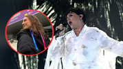Kobieta w czarnej bluzie z identyfikatorem, obok artysta w białej kreacji śpiewający na scenie.