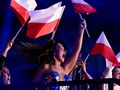 Ludzie świętują, trzymając flagi Polski, w radosnej atmosferze