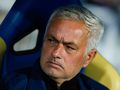 Jose Mourinho siedzi na ławce, z poważnym wyrazem twarzy, w sportowej odzieży.