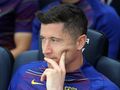 Na zdjęciu Robert Lewandowski, myślący, siedzi na ławce drużynowej w niebieskiej koszulce FC Barcelony.