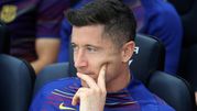 Na zdjęciu Robert Lewandowski, myślący, siedzi na ławce drużynowej w niebieskiej koszulce FC Barcelony.