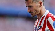Antoine Griezmann w czerwono-białym stroju Atletico Madryt, z zamyśloną miną, na stadionie.