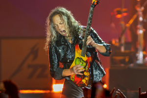 Muzyk grający na elektrycznej gitarze, z energią występuje na scenie przed publicznością.