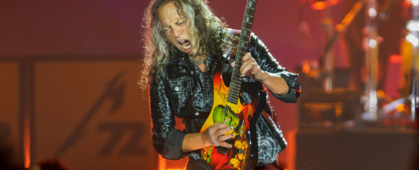 Muzyk grający na elektrycznej gitarze, z energią występuje na scenie przed publicznością.
