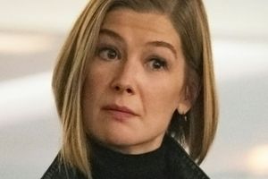 Kobieta z krótkimi blond włosami, w czarnym swetrze, patrzy z uwagą.