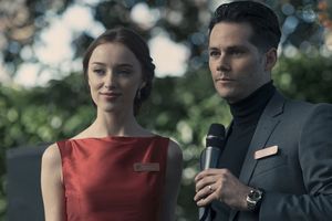 Para młodych ludzi na scenie, mężczyzna trzyma mikrofon, kobieta w czerwonej sukience.