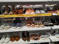 Na zdjęciu półki z różnorodnymi obuwiem na wyprzedaży, w tym sandały i sneakersy.