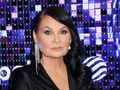 Iwona Pavlović eleganckiej stylizacji, z długimi włosami i świecącymi kolczykami.