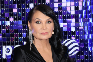 Iwona Pavlović eleganckiej stylizacji, z długimi włosami i świecącymi kolczykami.