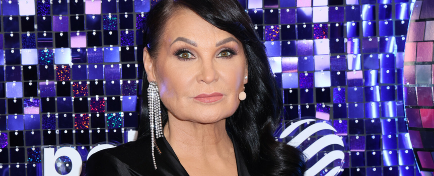 Iwona Pavlović eleganckiej stylizacji, z długimi włosami i świecącymi kolczykami.