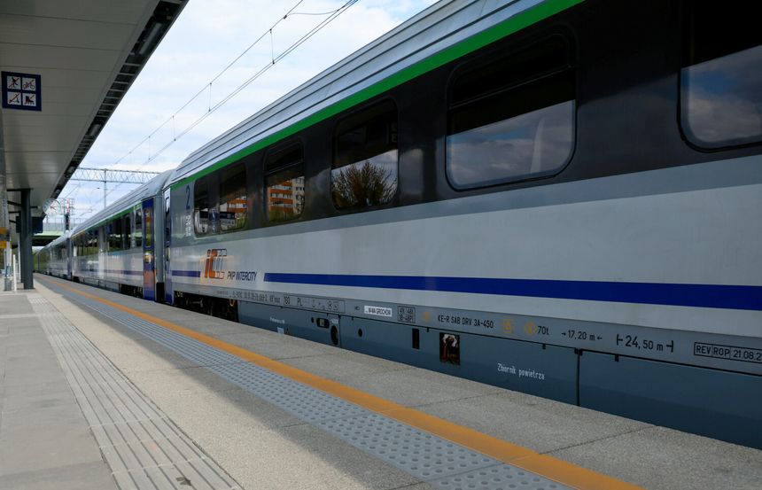 Pociąg PKP Intercity na stacji, obok peronu w nowoczesnym otoczeniu.