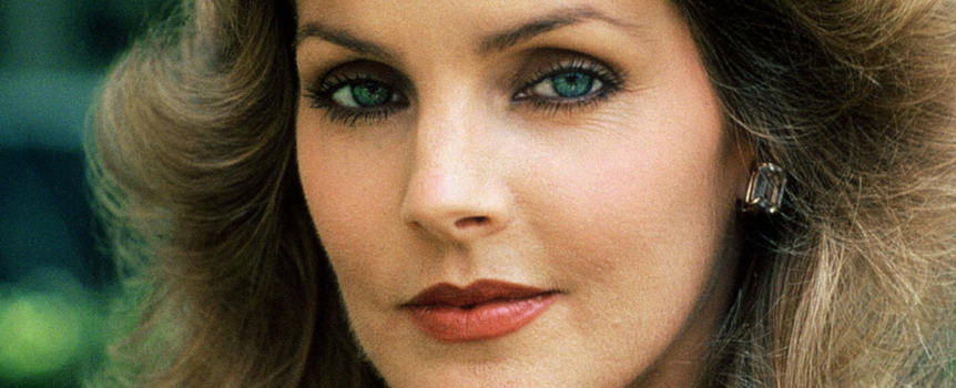 Priscilla Presley z długimi, falowanymi włosami i intensywnymi oczami.