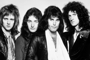 Muzycy z legendarnego zespołu Queen z długimi włosami w skórzanych kurtkach, w czarno-białym zdjęciu.