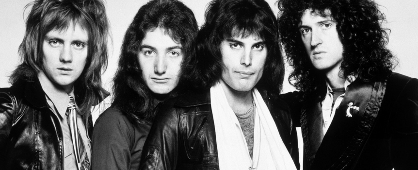 Muzycy z legendarnego zespołu Queen z długimi włosami w skórzanych kurtkach, w czarno-białym zdjęciu.