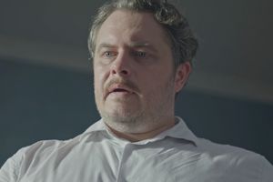 Mężczyzna w białej koszuli, widok z dołu, z wyrazem zdziwienia na twarzy.