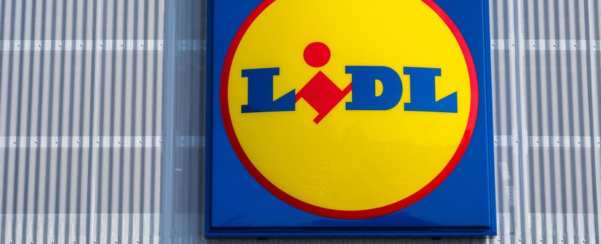 Znajduje się logo sklepu Lidl. Żółte kółko z niebieskim napisem na tle nieba.