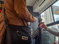 Osoby w autobusie, jedna skanuje bilet telefonem, druga trzyma telefon z kodem QR.