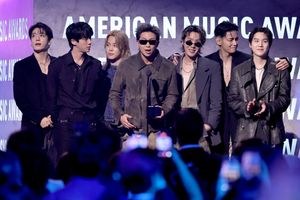 Czterech mężczyzn stoi na scenie w eleganckich strojach, trzymając nagrodę, w tle napisy AMERICAN MUSIC AWARDS.