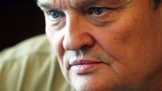 Zbliżenie na twarz mężczyzny z niebieskimi oczami i poważnym wyrazem twarzy.
