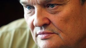 Zbliżenie na twarz mężczyzny z niebieskimi oczami i poważnym wyrazem twarzy.