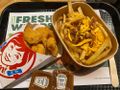 Obraz przedstawia zestaw fast food: nuggetsy, frytki z serem i sosem, podane na tacy.