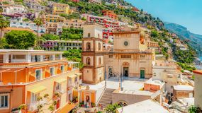Widok na kolorowe budynki w Positano, Włochy, z kościołem i górzystym krajobrazem w tle.