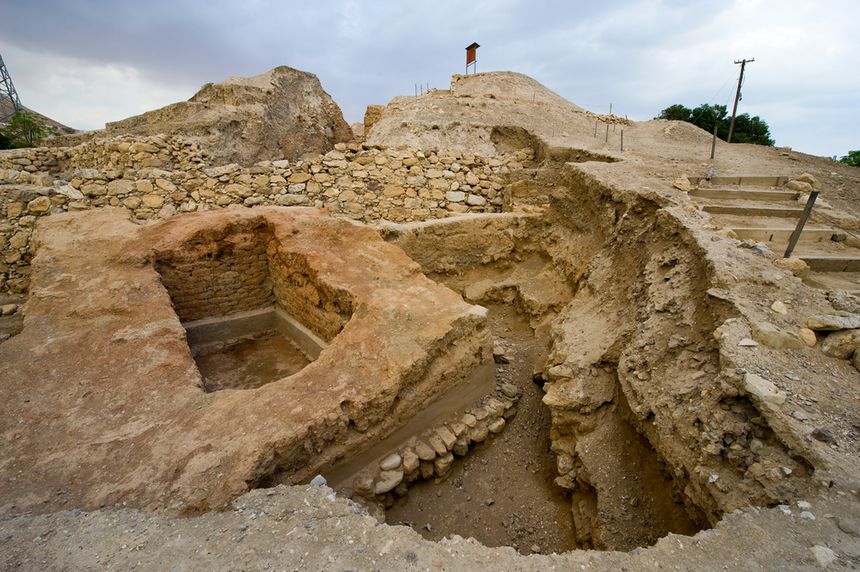 Zgliszczami historycznych ruin otoczone drogami i wzniesieniami. Szare niebo nad terenem.