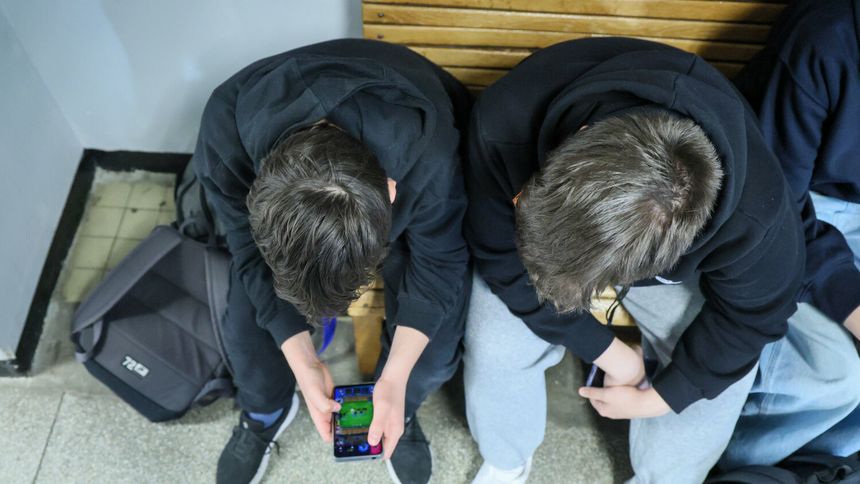 Uczniowie z telefonami na szkolnym korytarzu