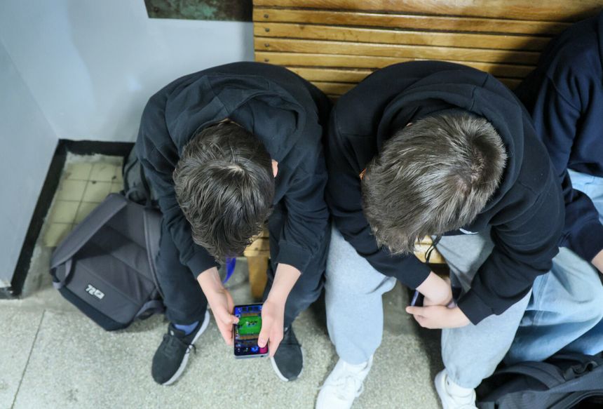 Uczniowie z telefonami na szkolnym korytarzu