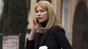 Kobieta w czarnym ubraniu, rozmawia przez telefon z kubkiem kawy w ręku.