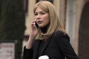 Kobieta w czarnym ubraniu, rozmawia przez telefon z kubkiem kawy w ręku.