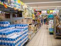 Zdjęcie przedstawia alejkę w sklepie spożywczym z półkami pełnymi produktów.
