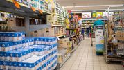 Zdjęcie przedstawia alejkę w sklepie spożywczym z półkami pełnymi produktów.