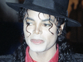 Michael Jackson z kręconymi włosami, w czarnym kapeluszu i czerwonej koszuli.