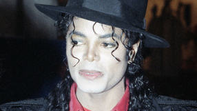 Michael Jackson z kręconymi włosami, w czarnym kapeluszu i czerwonej koszuli.