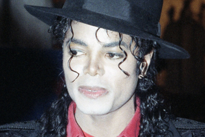 Michael Jackson z kręconymi włosami, w czarnym kapeluszu i czerwonej koszuli.