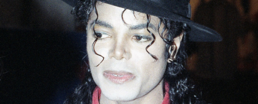 Michael Jackson z kręconymi włosami, w czarnym kapeluszu i czerwonej koszuli.